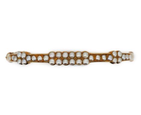 An Edwardian seed pearl bangle, early 20th century, of hinged design, set to the front with half seed pearls, mounted in gold