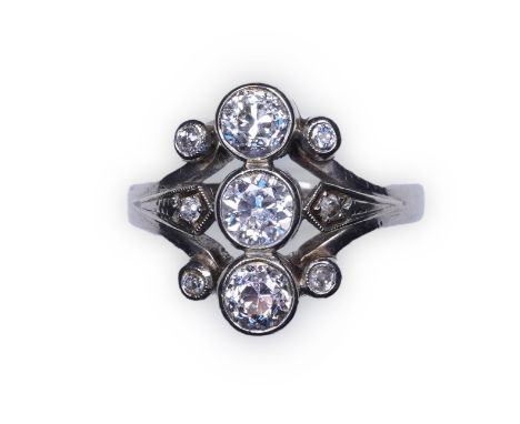 A diamond ring, set with a vertical line of three circular-cut diamonds totalling approximately 0.90 carats, between scrolled