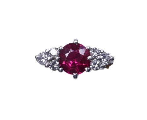 A synthetic ruby and diamond ring, claw-set with a circular-cut synthetic ruby between shoulders set with trios of brilliant-
