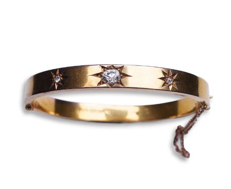 An Edwardian 15ct gold and diamond bangle, circa 1904, the hinged bangle set to the front with a sequence of three cushion-sh