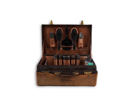A George V crocodile skin travelling toilet case, containing twelve silver and tortoiseshell mounted accoutrements, by Collet