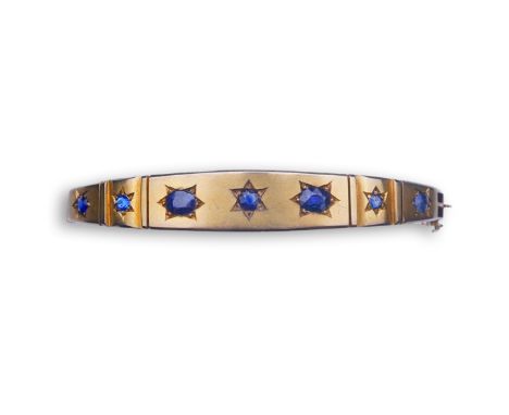 A Victorian sapphire bangle, late 19th century, of hinged design, the front set with a sequence of oval and circular-cut sapp