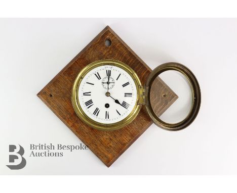Brass ship's clocks, white enamel face with Roman dial with second aperture, mounted to an oak plaque, approx 17 cms diameter