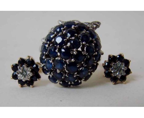 An 18K white gold cluster ring of oval form set with thirty-one small sapphires in three concentric bands within a partial fo