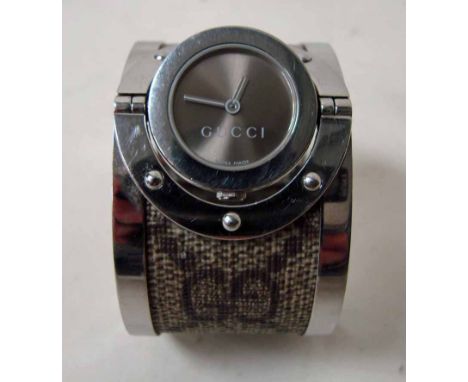 A modern ladies Gucci wrist watch, series 112 Twirl Bangle style with brown weave effect pattern to stainless bracelet, gimbl
