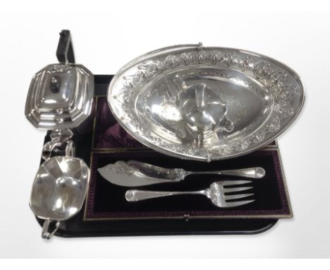 A silver-plated three-piece tea service, together with a pair of cased fish servers and an ornate swing-handled oval basket.