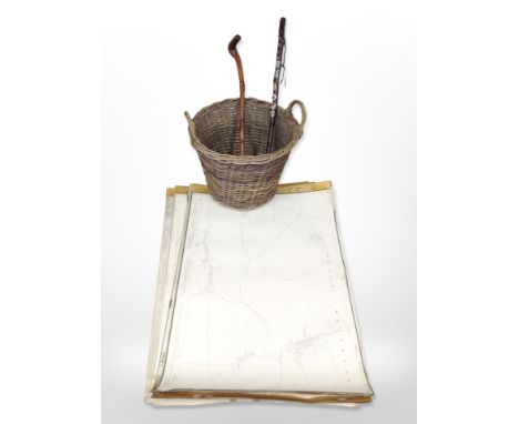 A twin-handled wicker hamper containing rolled maps 