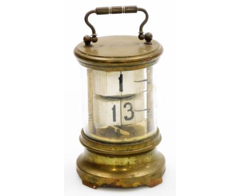 An early 20thC flip ticket clock, in a cylindrical brass coated tin case with Perspex front, and carrying handle, 16cm high. 