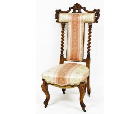 A Victorian walnut prie dieu chair, with foliate carving and bobbin turned back supports, overstuffed with striped floral uph
