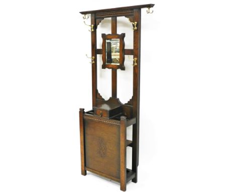 An early 20thC oak hall stand, with six coat hooks, a mirror back above a glove box and umbrella stand, raised on stile suppo