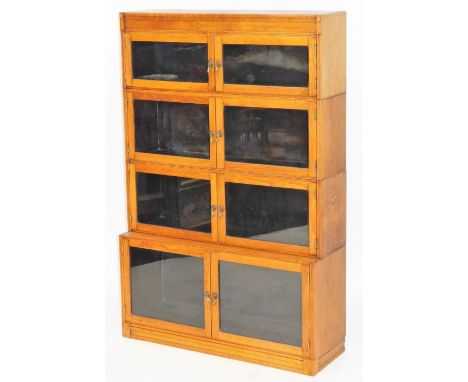 An early 20thC light oak bookcase, of four graduated sections each with glazed doors, raised on a plinth base, 134cm high, 89