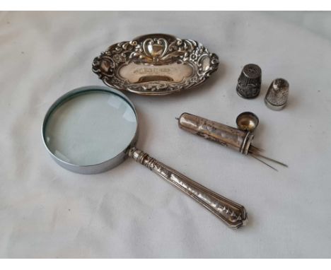 A silver handled magnifying glass, an oval dish, two thimbles and a cigarette holder