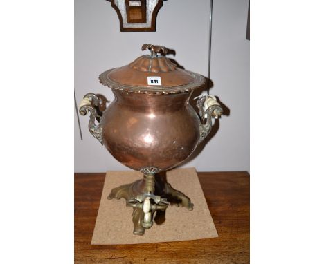 A copper and brass tea urn with ceramic handles.