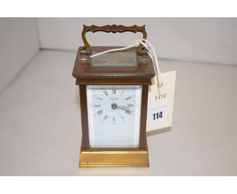 A brass carriage clock with enamelled dial and roman numerals.