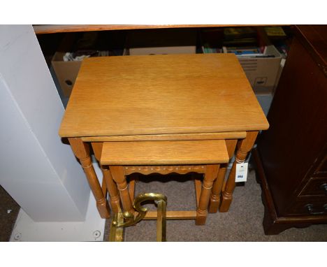 A nest of three light stained oak occasional tables.
