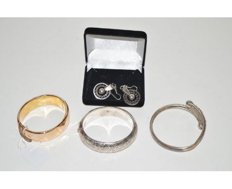 A yellow metal bangle; two white meal bangles; and a pair of white metal drop earrings.