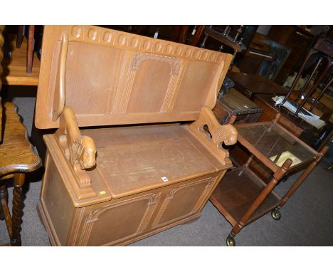 A light stained oak monk's bench, the panel top hinged on lion pattern arms, box seat under.