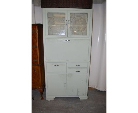 A green painted larder cabinet, with etched glass panels above a fall-flap with enamel surface, drawers and cupboard doors un