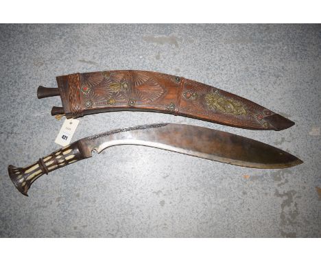 A large ornamental kukri with inlaid bone handle and wooden scabbard.