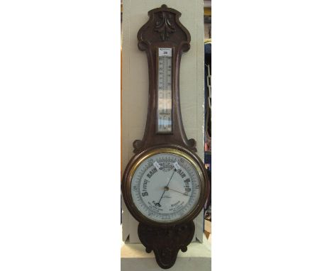 Early 20th Century oak wheel barometer, ceramic face and thermometer scale, marked: Crouch, Cardiff and Newport.  80cm high a