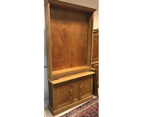 An early to mid 20th Century light oak bookcase cabinet, the upper section with adjustable shelving over two cupboard doors o