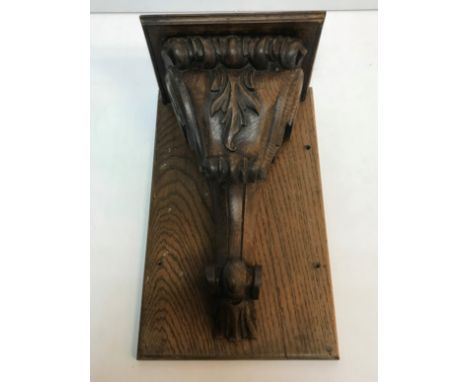 A carved oak corbel with stylised foliate decoration mounted on a wooden back, total size 41.5 cm x 25.5 cm x 18 cm deep