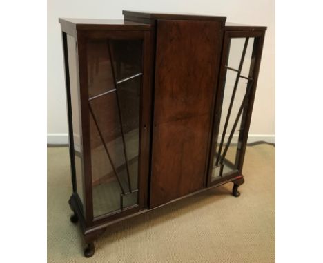 A 1930s walnut display cabinet of stylised sunburst form, the central quartered door flanked by two glazed cupboard doors rai