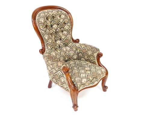 A Victorian mahogany spoon back nursing chair, upholstered in button back multicoloured foliate fabric, with overstuffed seat