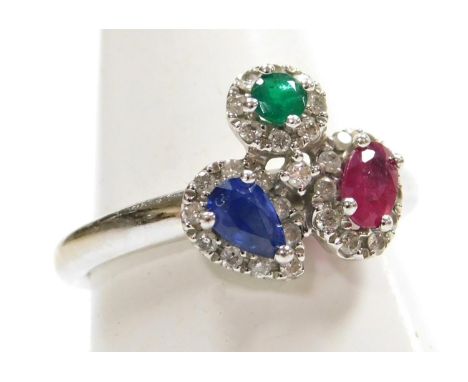 A ruby sapphire and emerald ring, set with a brilliant cut emerald, oval cut ruby, and pear shaped sapphire, each in a surrou