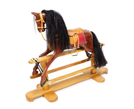 A rocking horse, with a tan leather saddle and bridle, raised on a light oak base, 133cm wide.