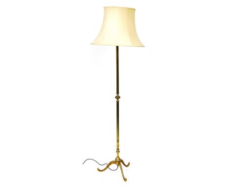 An early 20thC brass standard lamp, raised on three leaf capped cabriole legs, with a cream shade, 177cm high.Buyer Note: WAR
