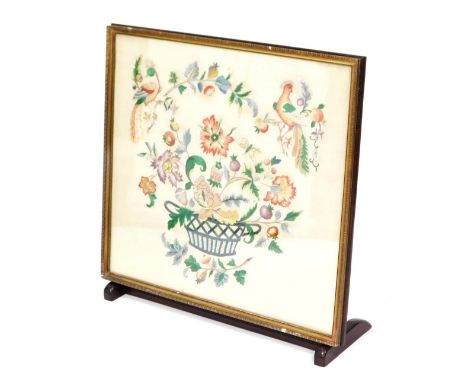 An early 20thC wool work tapestry fire screen, embroidered with birds, fruit and flowers, within a gilt frame, on an integral