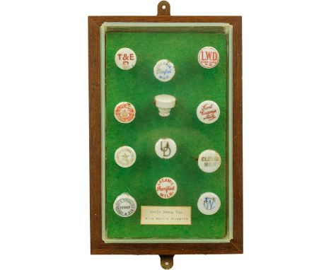 A framed display of ceramic bottle stoppers. Mostly diary companies, 28.5cm x 18.5cm. 
