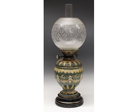A Doulton Lambeth  oil lamp, of ovoid form applied with floral swags and birds in buff on a mottled blue ground,  the shoulde