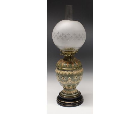 A Doulton Lambeth  oil lamp, of ovoid form applied with floral swags and birds in buff on a mottled blue ground,  the shoulde