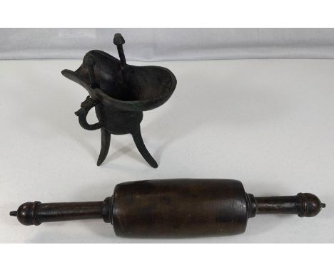 A Chinese bronze Jue libation vessel on three legs and an Indian antique rolling pin.
