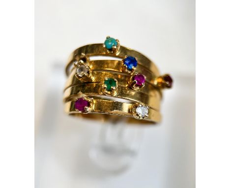 A yellow metal ring with 5 adjoined shanks set with a total of 9 multicoloured stones including ruby, sapphire, emerald, turq