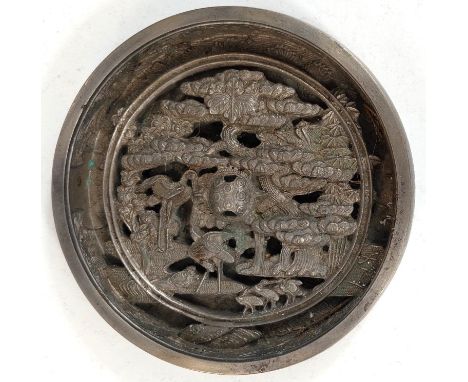 A Chinese white metal mirror with highly decorated, pierced back, with animals, birds and trees etc. 