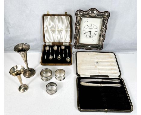 A silver mounted mantle clock; a selection of silver teaspoons, cased; a posy vase and napkin rings. 