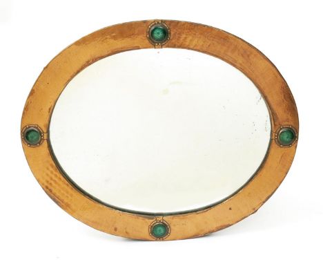 A copper wall mirror probably retailed by Liberty & Co, oval, set with green enamel roundels unsigned 64.5cm. wide
