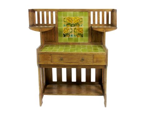 A Liberty & Co oak wash stand designed by Leonard Wyburd, set with green square tiles, the shelved slat-back set with similar