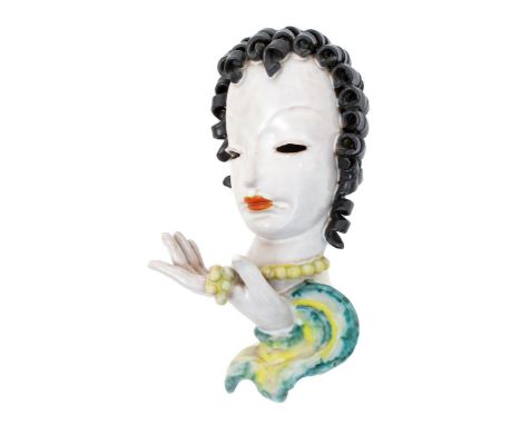 A Goldscheider Pottery wall mask, model no.7121, modelled as a stylised woman her hand raised to hold her yellow bead necklac