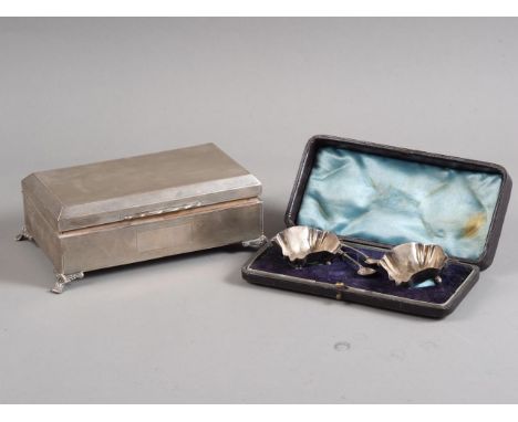 A silver engine turned cigarette box and a pair of silver salts and spoons, in case 