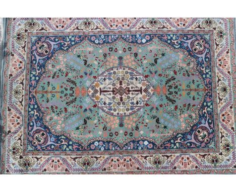 A wool pile rug of Persian design with central white medallion on a light green ground and all-over floral design, in shades 