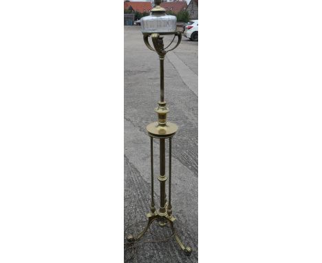 An Edwardian brass adjustable standard oil lamp (now converted to electricity), on tripod scroll support, 53" high 