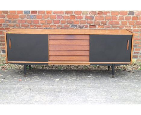 A 1960s teak and ebonised panel sliding door sideboard, fitted five centre drawers, on ebonised turned supports, 75 1/2" wide