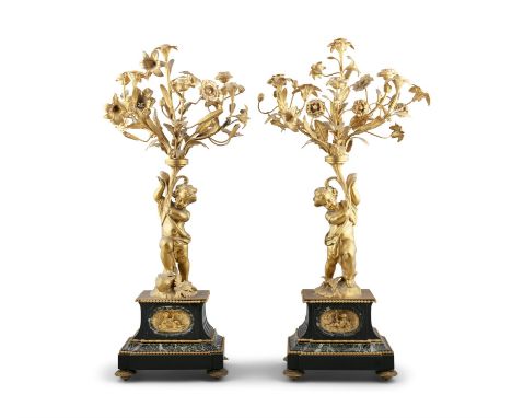 A PAIR OF MID 19TH CENTURY GILT BRASS FIGURAL CANDELABRA, each with six foliate candle sconces supported by a putto, standing