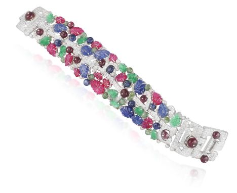 A GEM-SET AND DIAMOND BRACELET, of 'tutti frutti' design, the wide strap set with carved ruby, sapphire and emerald leaves an