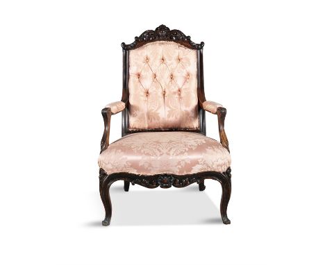 A FRENCH 19TH CENTURY CARVED WALNUT FRAMED UPHOLSTERED ARMCHAIR, the crest rail with foliate scrollwork above a button back, 