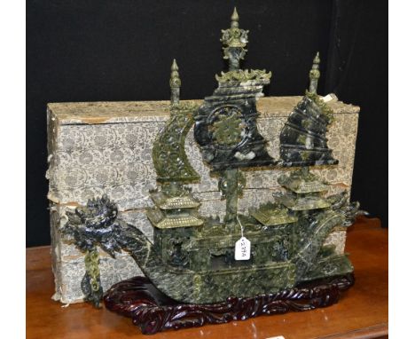 A large Chinese green jade model, of a three-mast junk, the bow, hull and stern carved as a pair of ferocious dragons with sc